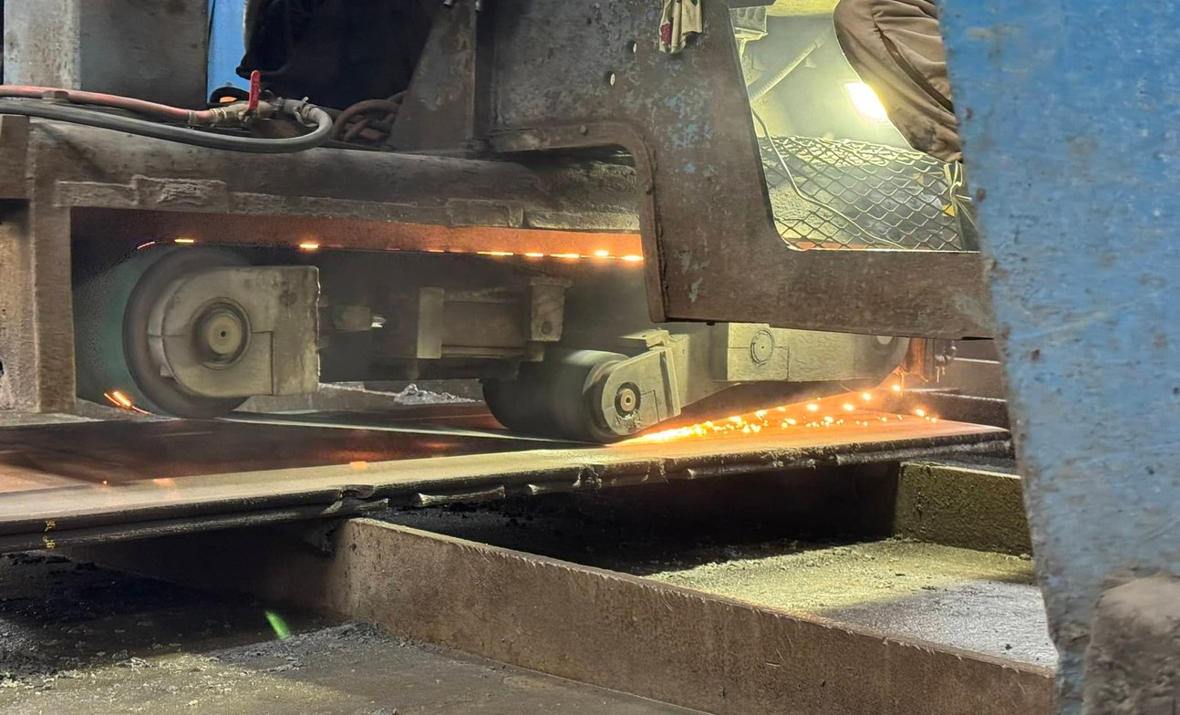 Bandsaw blade cutting through steel plate with glowing sparks