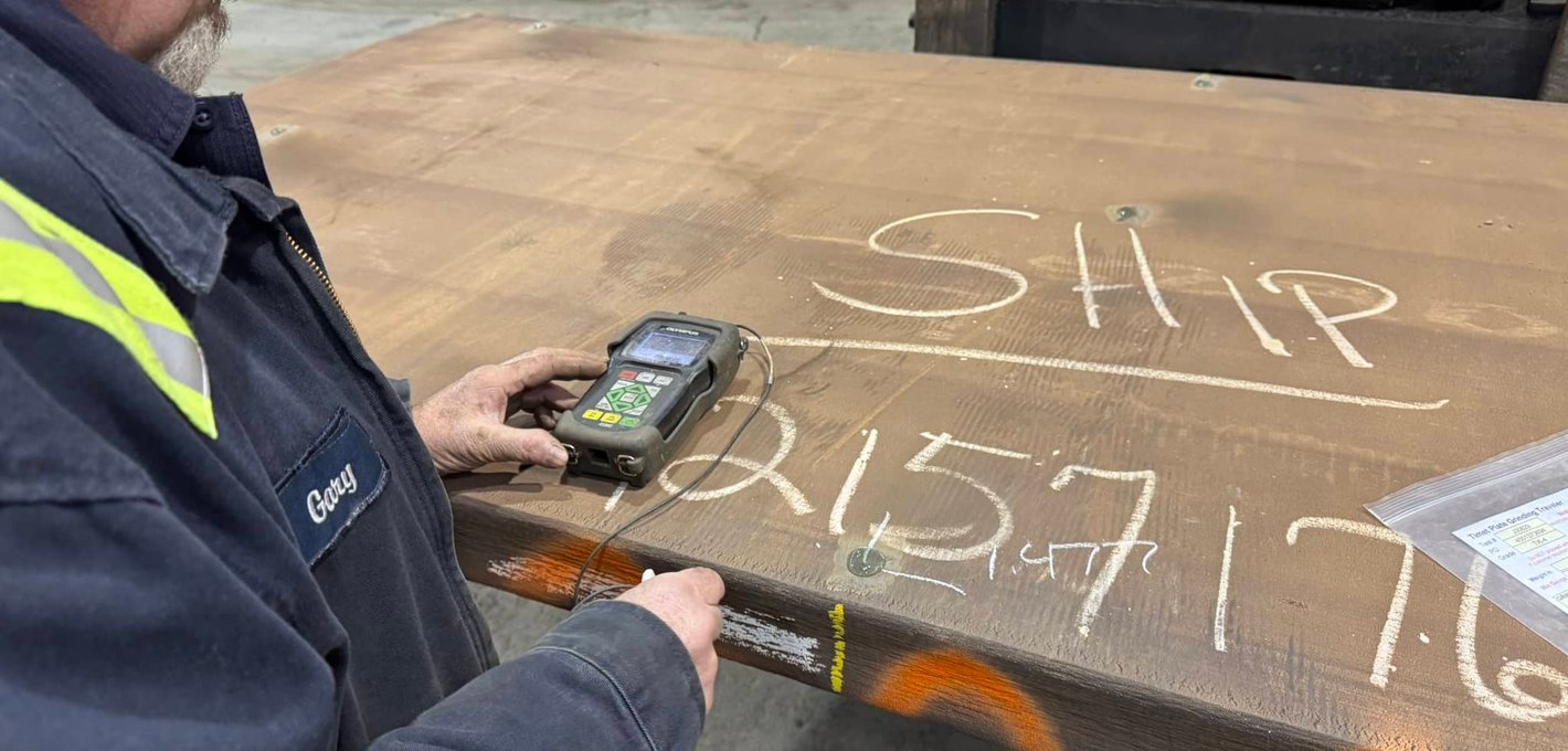 Technician using ultrasonic thickness gauge to inspect a steel plate