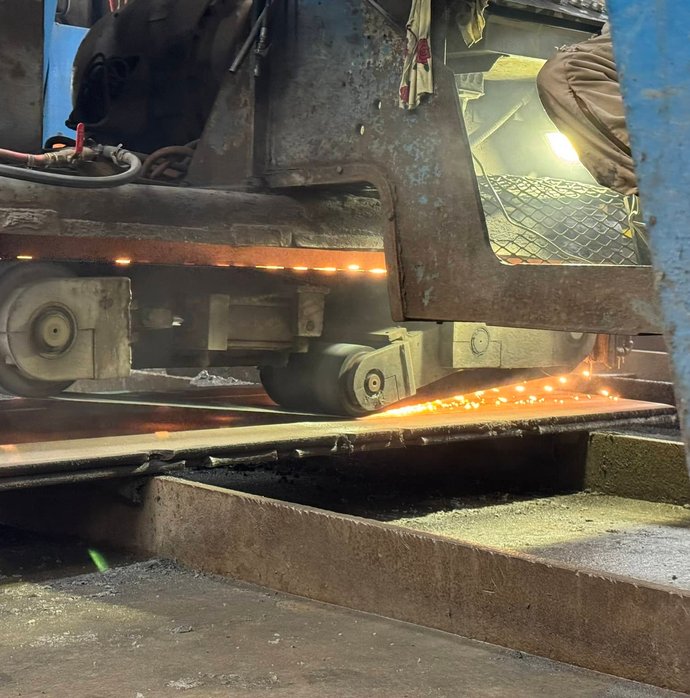 Bandsaw blade cutting through steel plate with glowing sparks