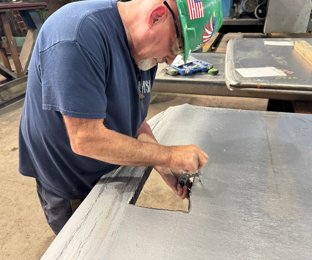 Technician inspecting a cleared spot on incoming plate before grinding