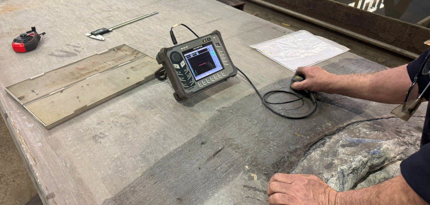 Technician using ultrasonic thickness gauge to inspect a steel plate